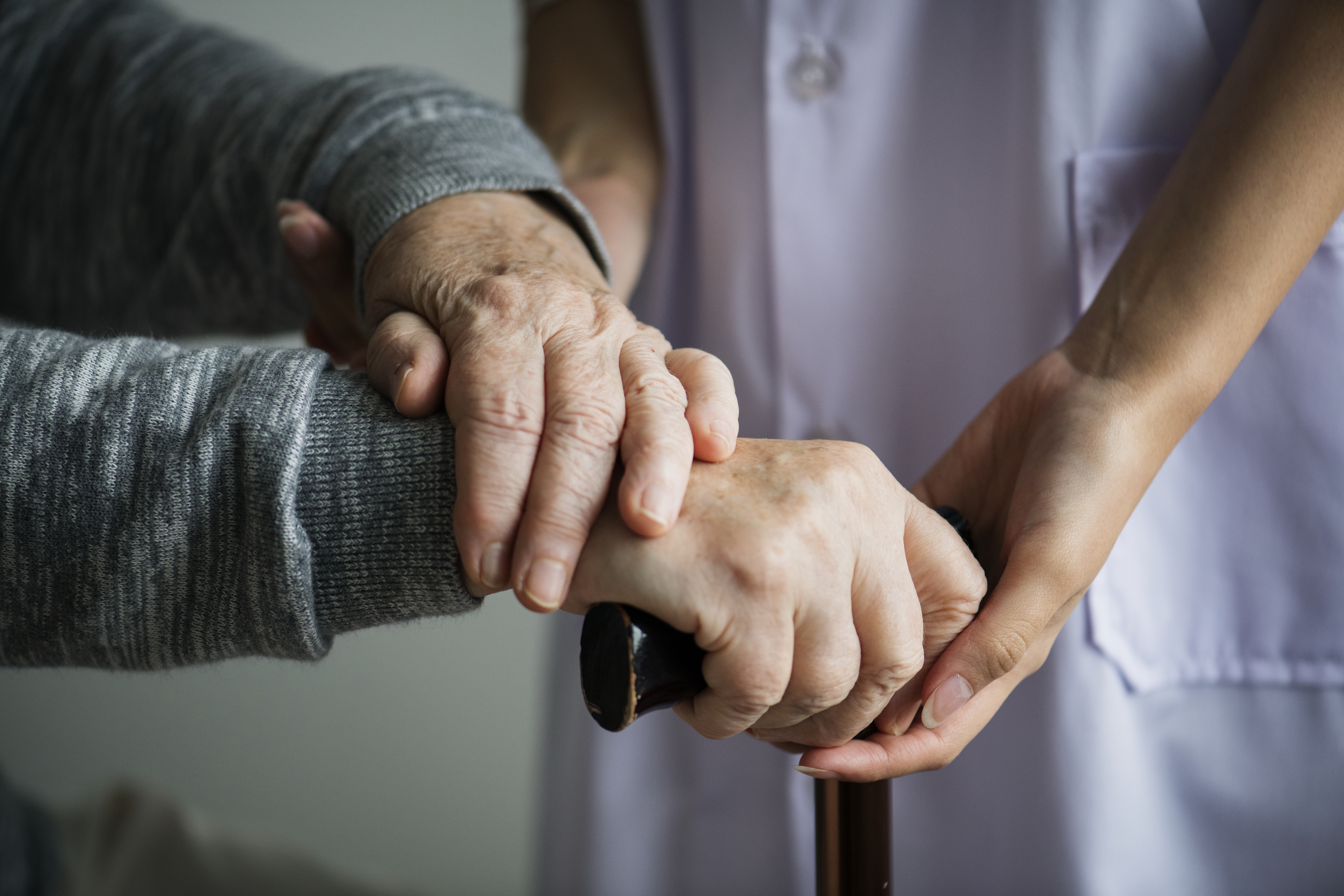 Close-up of a caregiver's hands gently holding a senior's hands, symbolizing support.
